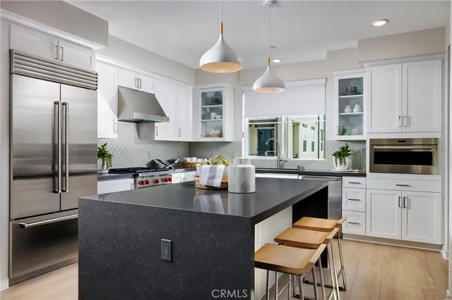 a kitchen with kitchen island a stove a sink a oven and a refrigerator