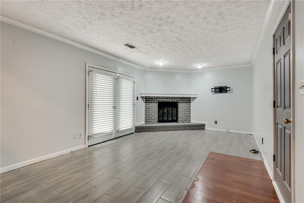 5611 Whittondale Road Lithonia, GA 30058 - Photo 15 of 34 an empty room with wooden floor fireplace and windows