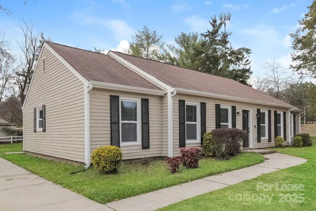 a view of a house with a yard plants and large tree