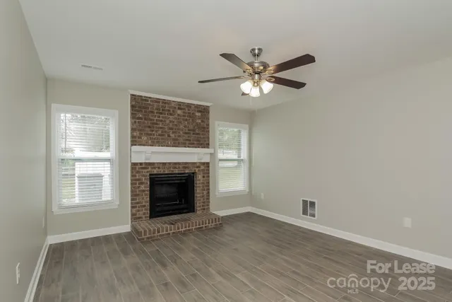 an empty room with windows fireplace and wooden floor