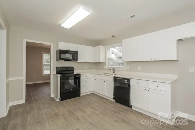 a kitchen with granite countertop white cabinets and stainless steel appliances