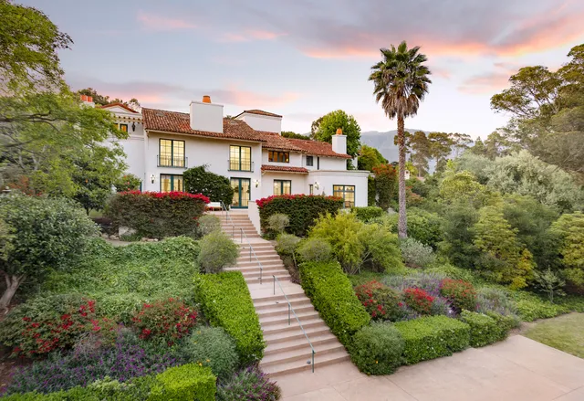 a front view of a house with a yard and potted plants