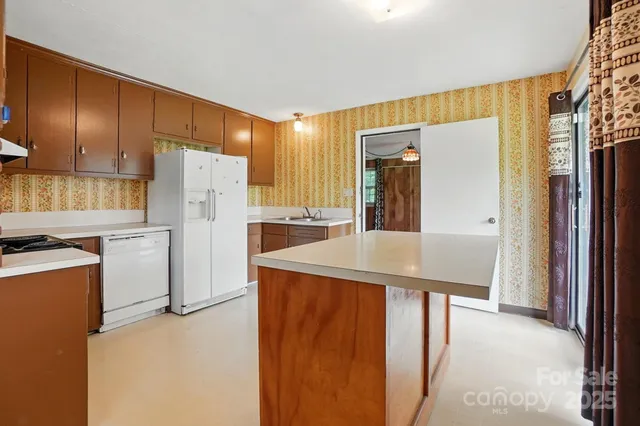 a kitchen that has a refrigerator a stove and a sink with wooden floor