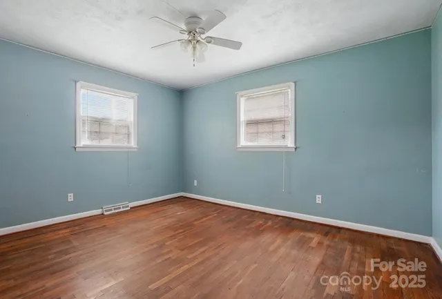 a view of an empty room with a window and wooden floor