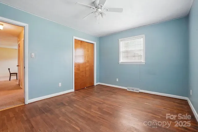 an empty room with a chandelier fan and windows