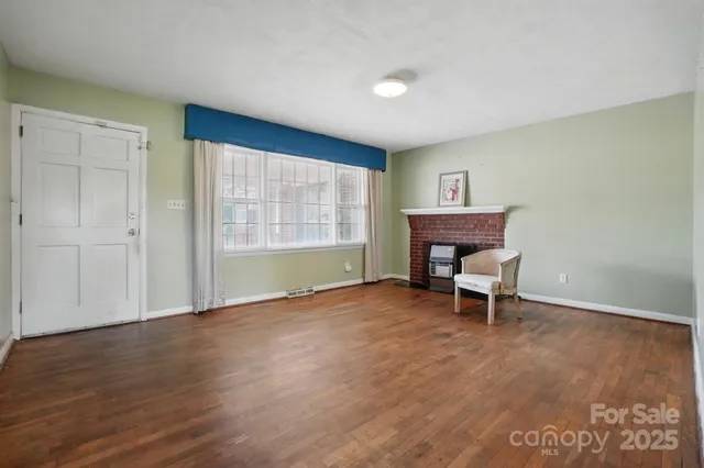 a view of an empty room with a window and a fireplace