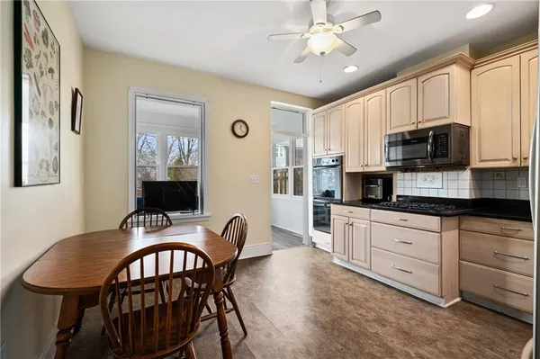 a kitchen with stainless steel appliances granite countertop a dining table chairs refrigerator and microwave