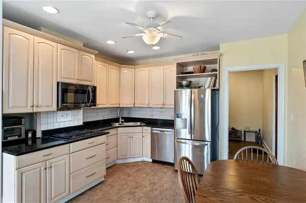 a kitchen with granite countertop a refrigerator a sink a stove and cabinets