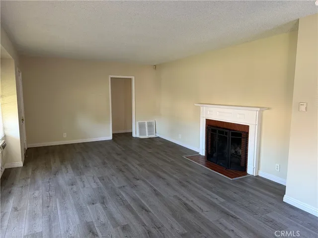 an empty room with wooden floor and a fireplace