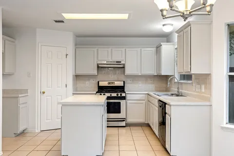a kitchen with a stove sink and cabinets