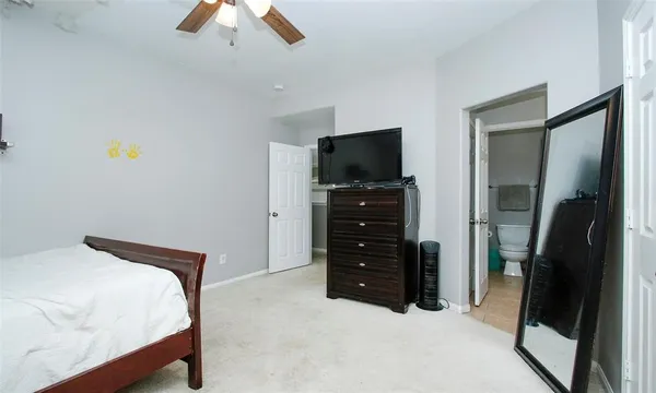 a bedroom with a bed and a flat tv screen on dresser