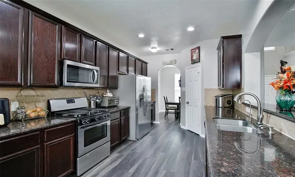 a kitchen with stainless steel appliances granite countertop a stove refrigerator and microwave
