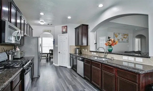 a kitchen with stainless steel appliances granite countertop a sink stove and cabinets