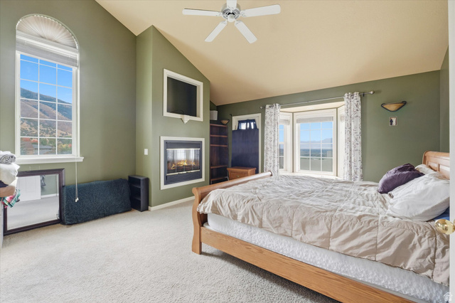 2887 View Crest Circle North Logan, UT 84341 - Photo 23 of 37 Carpeted bedroom featuring a glass covered fireplace, a ceiling fan, and vaulted ceiling