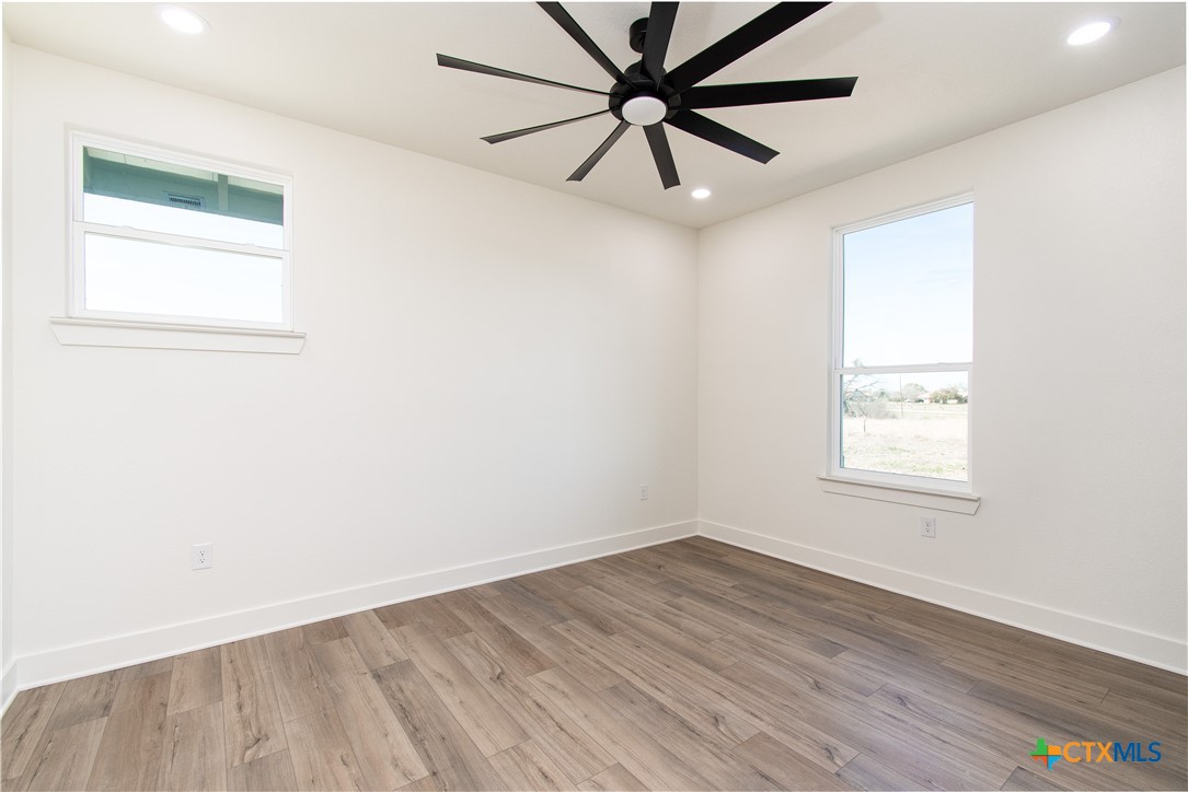4245 Stringtown Road Temple, TX 76501 - Photo 16 of 25 an empty room with wooden floor ceiling fan and windows