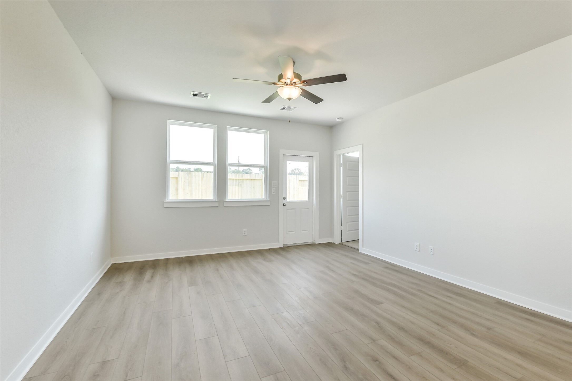 25984 Liberation Road Cleveland, TX 77328 - Photo 9 of 35 an empty room with wooden floor ceiling fan and windows