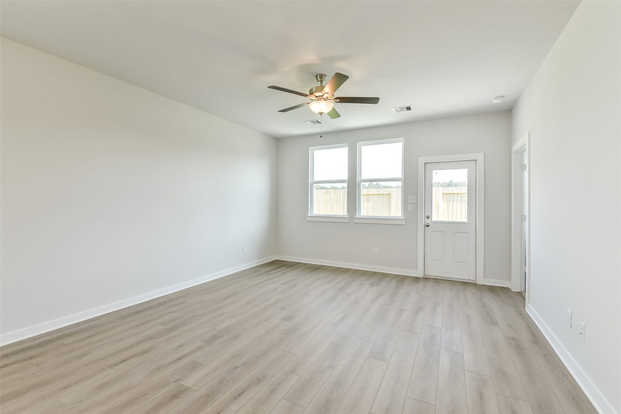 25984 Liberation Road Cleveland, TX 77328 - Photo 10 of 35 an empty room with wooden floor ceiling fan and windows