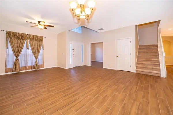 a view of empty room with wooden floor and fan