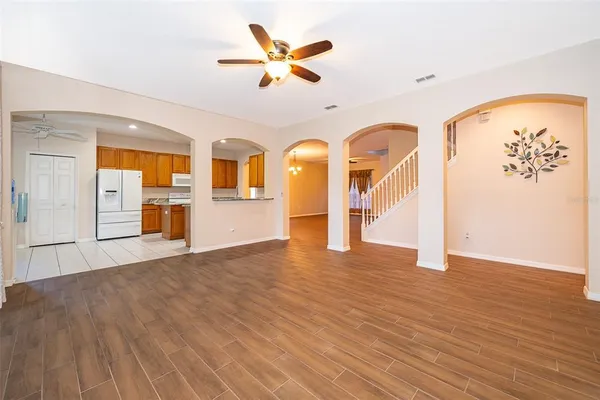 a view of an empty room with wooden floor and a ceiling fan