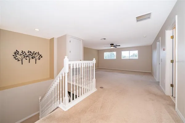 an empty room with windows and ceiling fan