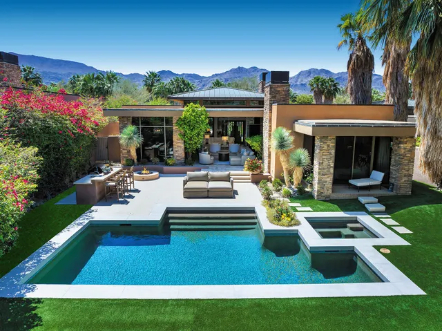 a view of a house with swimming pool lawn chairs and a yard