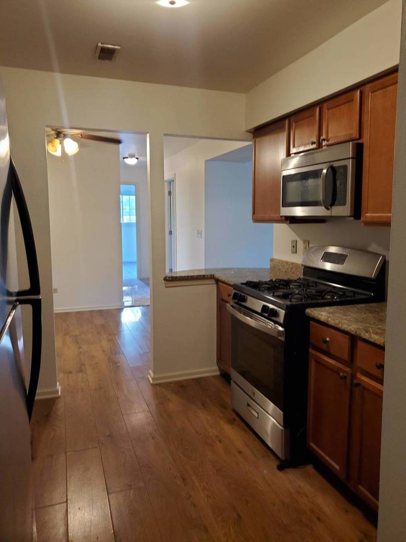 833 Village Quarter Road, Unit G4 West Dundee, IL 60118 - Photo 5 of 15 a kitchen with stainless steel appliances a stove a microwave and a hard wood floor