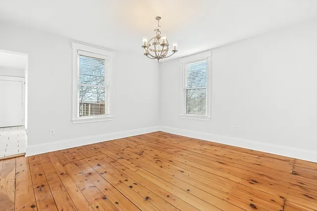 a view of a room with wooden floor and a chandelier fan