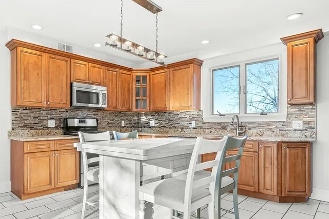 a kitchen with stainless steel appliances granite countertop a stove a sink dishwasher a stove a refrigerator with a dining table and chairs