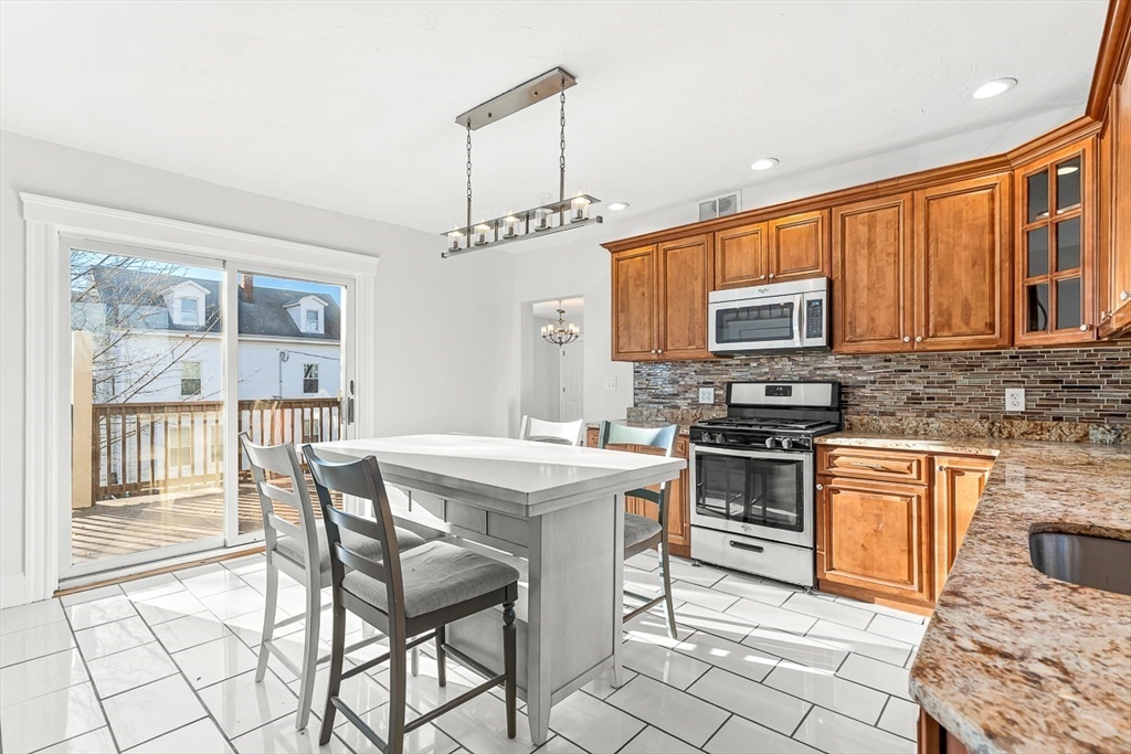 11 Symonds Street, Unit 2 Salem, MA 01970 - Photo 9 of 30 a kitchen with stainless steel appliances granite countertop a stove a sink dishwasher a stove a refrigerator with a dining table and chairs