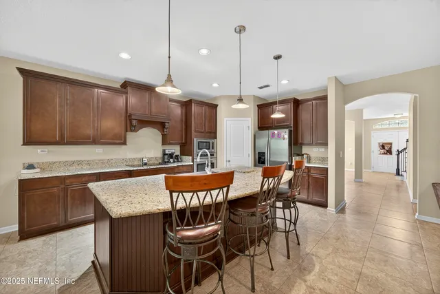 a kitchen with stainless steel appliances granite countertop a stove a sink a refrigerator and a fireplace