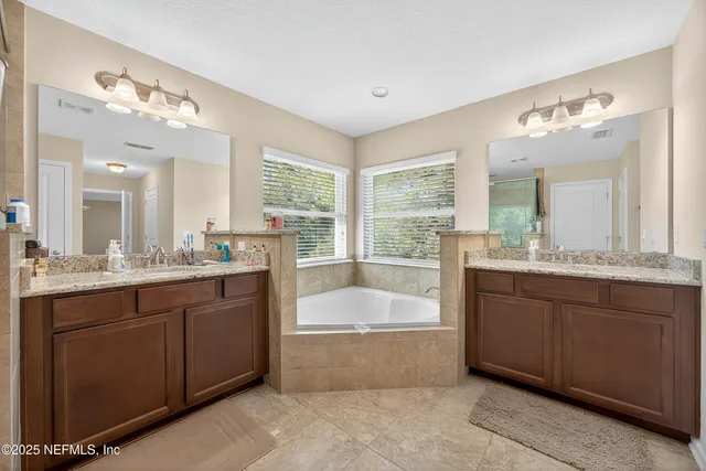 a spacious bathroom with a tub sink and mirror