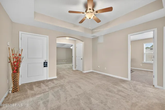 an empty room with closet and a ceiling fan