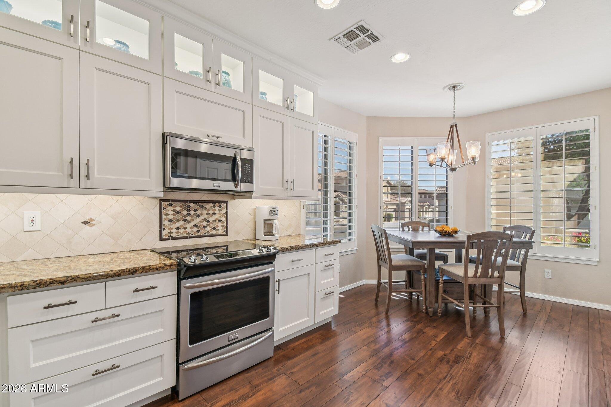 1024 East Frye Road, Unit 1039 Phoenix, AZ 85048 - Photo 7 of 32 a kitchen with granite countertop stainless steel appliances a dining table chairs stove microwave and cabinets