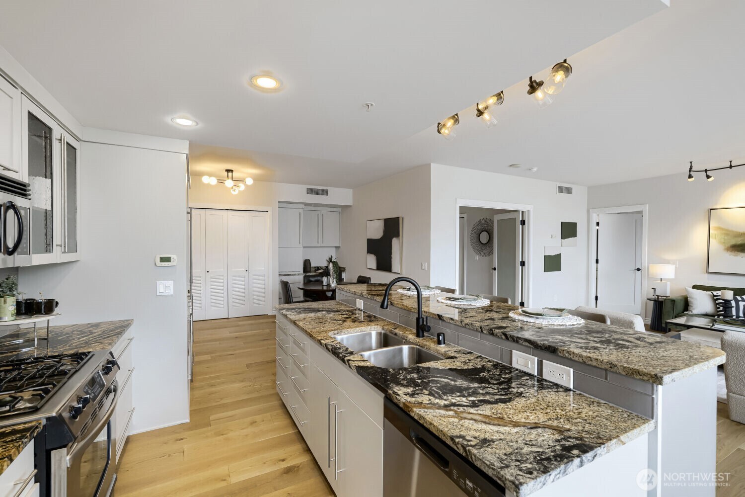 76 Cedar Street, Unit 1109 Seattle, WA 98121 - Photo 14 of 28 a large kitchen with kitchen island a stove a sink dishwasher and a dining table with wooden floor