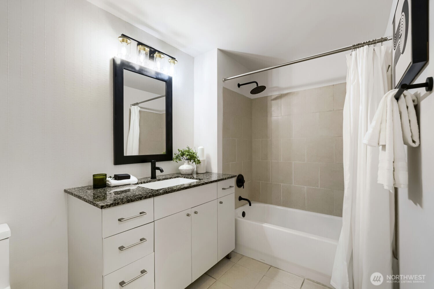 76 Cedar Street, Unit 1109 Seattle, WA 98121 - Photo 25 of 28 a bathroom with a granite countertop sink a mirror a vanity and a bathtub