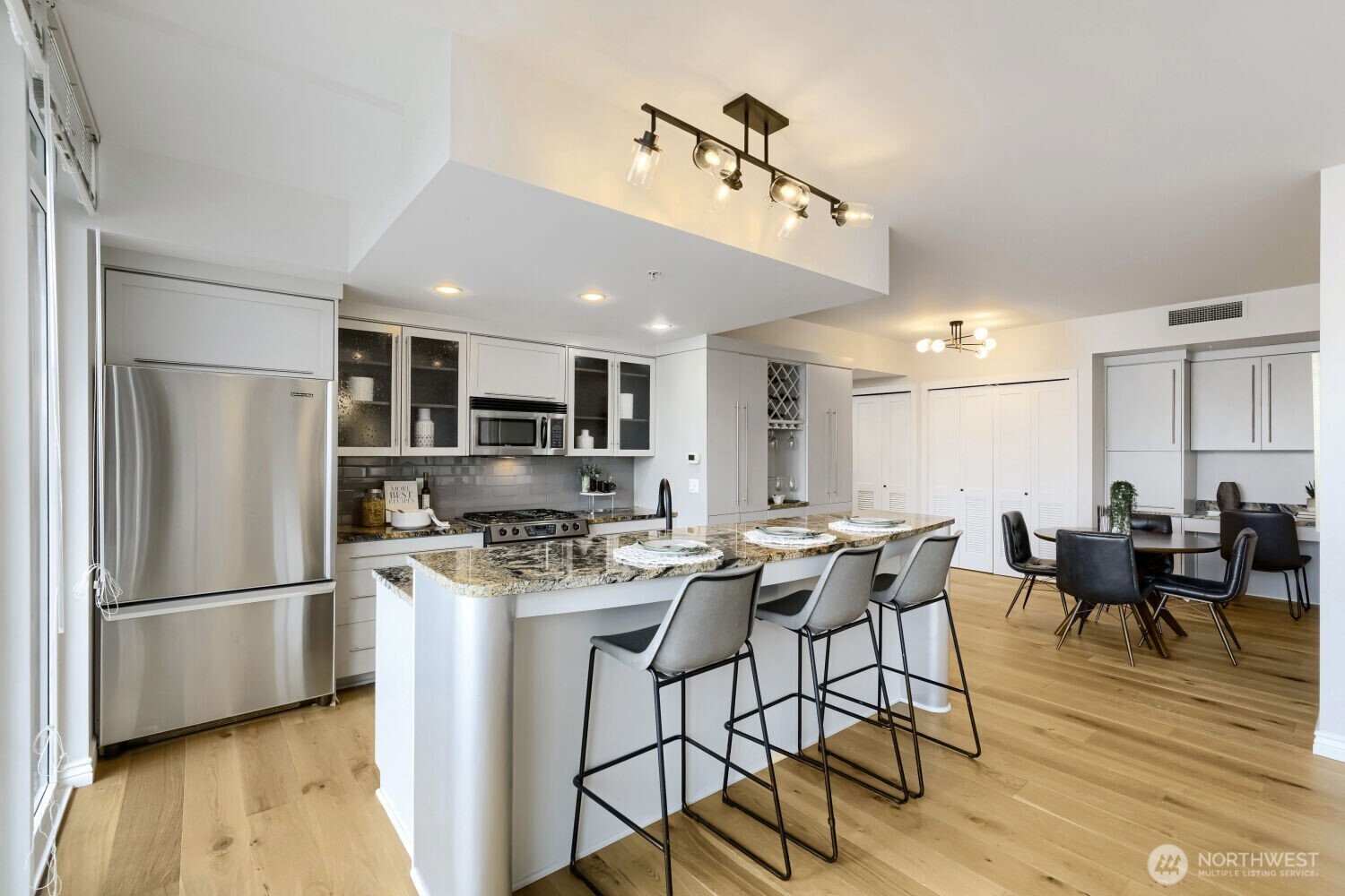 76 Cedar Street, Unit 1109 Seattle, WA 98121 - Photo 10 of 28 a kitchen with stainless steel appliances granite countertop a dining table chairs stove refrigerator and cabinets