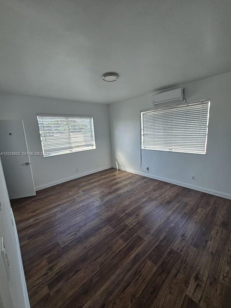 855 80th Street, Unit 4 Miami Beach, FL 33141 - Photo 7 of 16 an empty room with wooden floor and windows