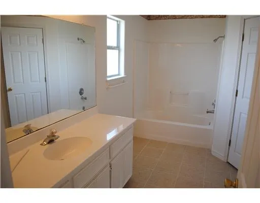 a bathroom with a tub sink vanity granite and a mirror