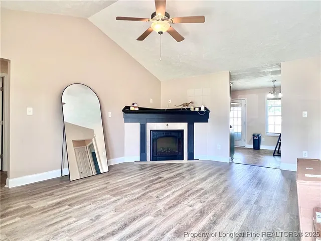 a view of a livingroom with a fireplace a chandelier and wooden floor
