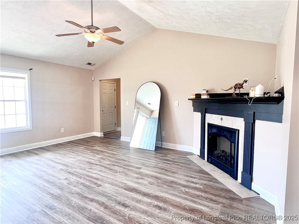 285 Pebble Lane Raeford, NC 28376 - Photo 4 of 7 a view of a livingroom with a fireplace a chandelier a wooden floor and windows