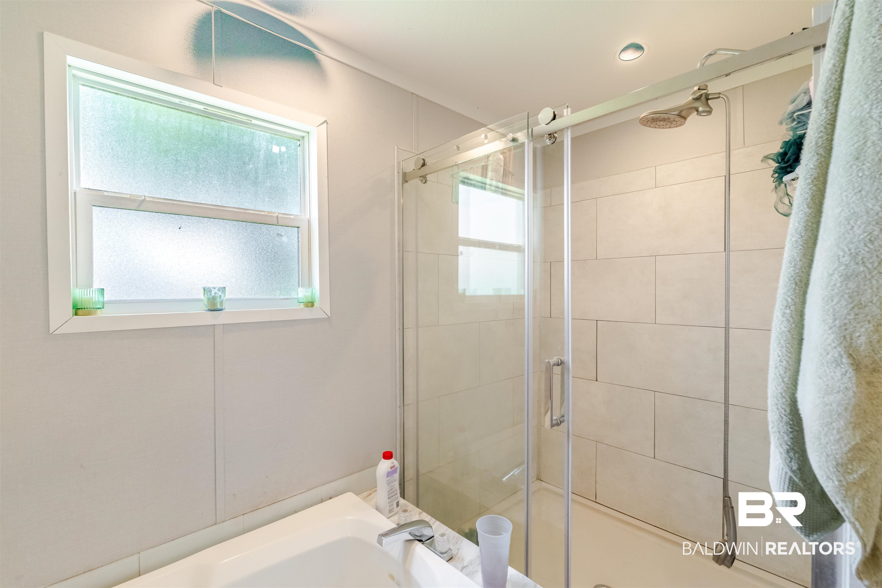 15575 Mikkelsen Road Summerdale, AL 36580 - Photo 19 of 68 Contemporary bathroom featuring a sliding glass shower door, tiled shower surround, recessed lighting, and a window with privacy glass
