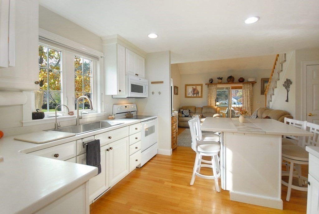 110 Summer Road, Unit 110 Boxborough, MA 01719 - Photo 8 of 28 a kitchen with stainless steel appliances kitchen island granite countertop a sink and cabinets