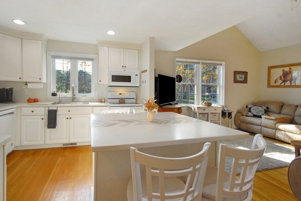 110 Summer Road, Unit 110 Boxborough, MA 01719 - Photo 9 of 28 a kitchen with kitchen island a stove a sink a dining table and chairs
