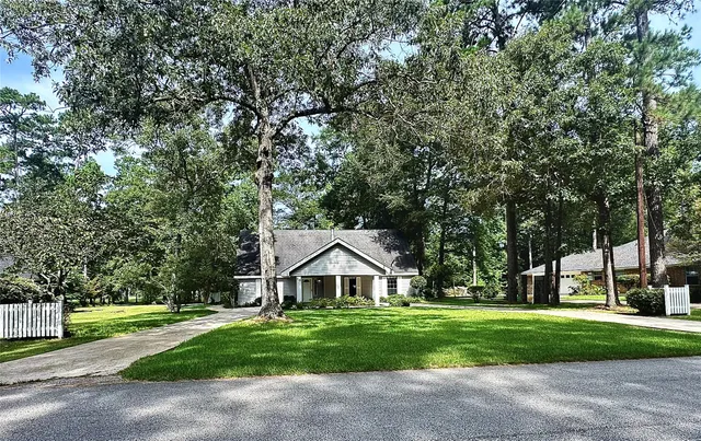 a front view of a house with a yard and large trees