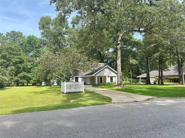 a front view of a house with a yard and large trees