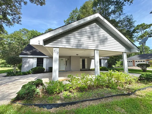 a view of a house with a yard and potted plants