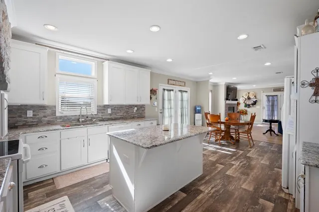 a large kitchen with granite countertop a sink and white cabinets