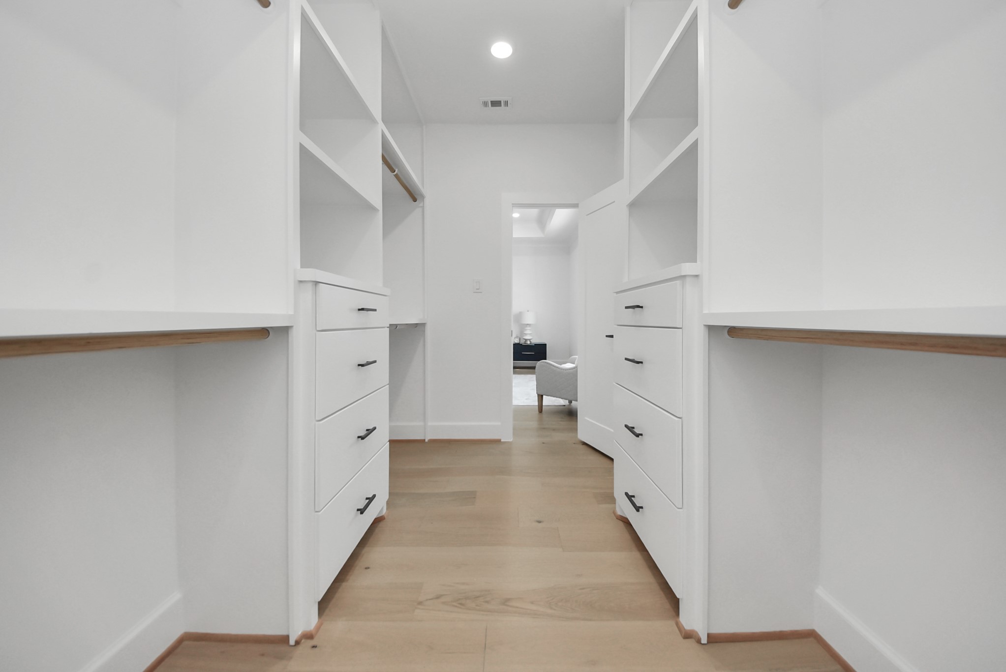 925 Fisher Street, Unit E Houston, TX 77018 - Photo 24 of 47 Step into this expansive walk-in closet, featuring ample shelving, drawers, and hanging space. Light wood flooring and white cabinetry create a bright, modern environment, offering plenty of storage and organization for everyday living.