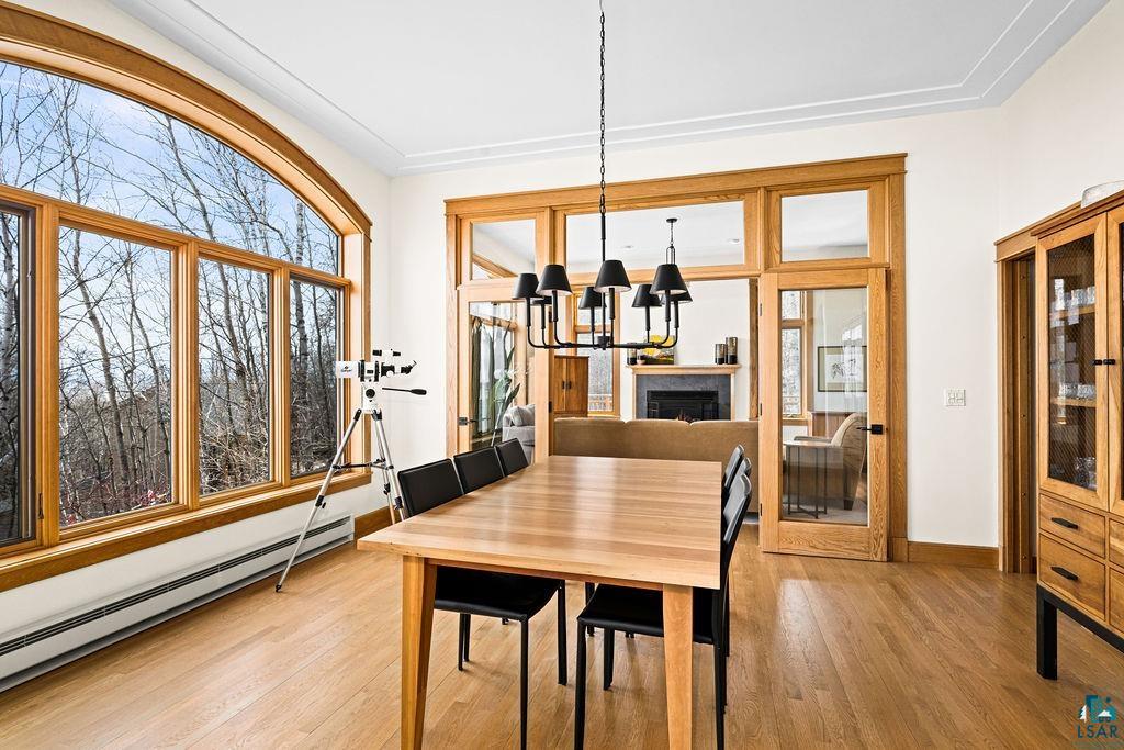 4856 Kingston Street Duluth, MN 55804 - Photo 3 of 88 Dining area featuring expansive arched windows with natural wood trim, wood-finish flooring, a contemporary black metal chandelier, and a built-in display cabinet with glass doors