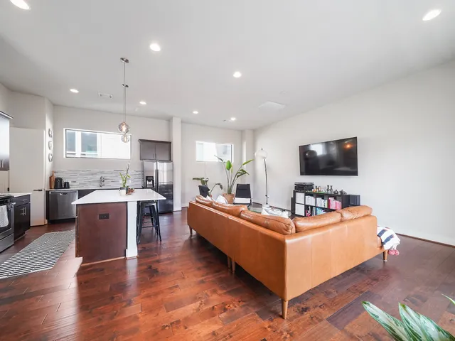 a living room with furniture a flat screen tv and kitchen view
